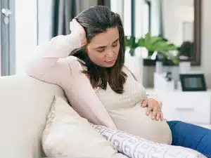 زنی باردار که نگران است و بر روی نشسته است